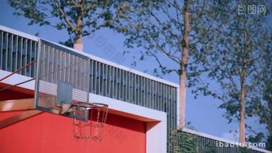 橙色球飞过篮球场,在阳光明媚的夏日用金属链网从篮子里落下。现代城市红色运动场的概念。得分赢点。三重拍摄.
